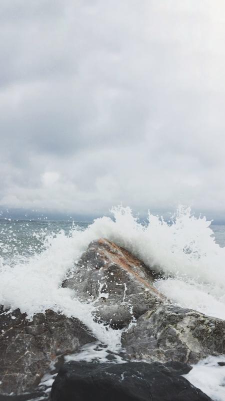 Person Taking Photo of Sea Waves and Gray Concrete Rock