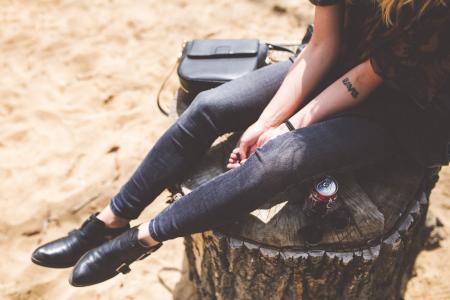 Person Wearing a Blue Denim Jeans and Black Leather Shoes Sitting on a Trunk