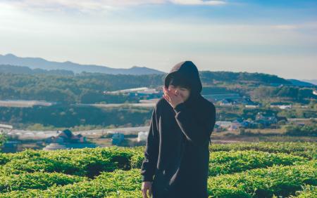 Person Wearing Black Hoodie Surrounded by Vegetables