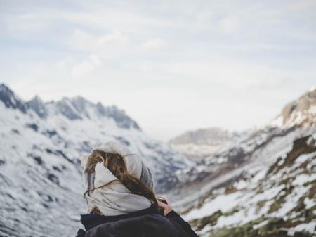 Person Wearing Black Jacket in Front of Mountain Filled With Snow