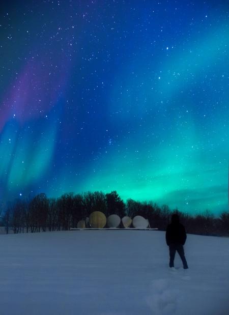 Person Wearing Black Jacket Standing on Snowy Field during Nighttime