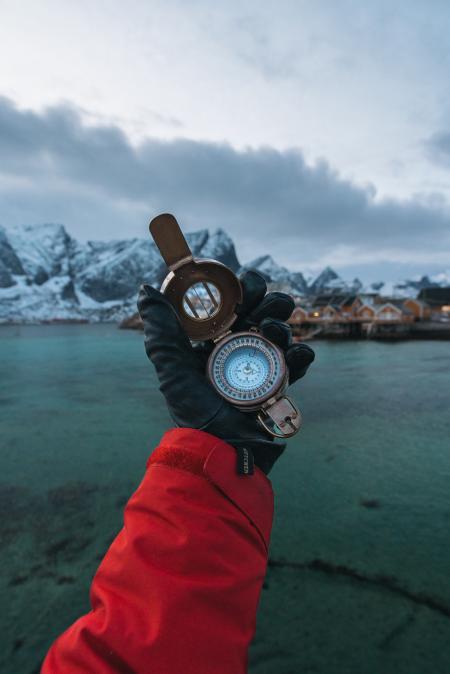 Person Wearing Black Leather Gloves Holding Brass-colored Compass