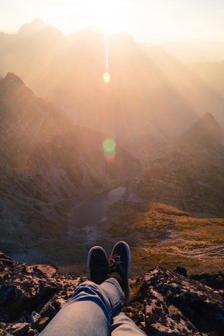 Person Wearing Black Sneakers Sitting in Mountain