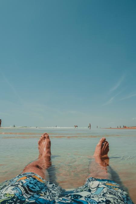 Person Wearing Doodled Boardshorts Sitting on Surface With Water