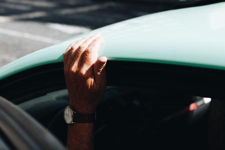 Person Wearing Round White Analog Watch Black Strap Holding on Vehicle Roof