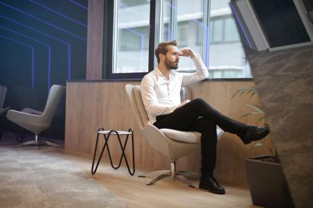 Photo of a Man Sitting Near the Windoww