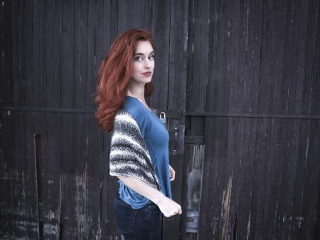 Photo of a Woman Wearing Blue Shirt Behind Black Wooden Wall