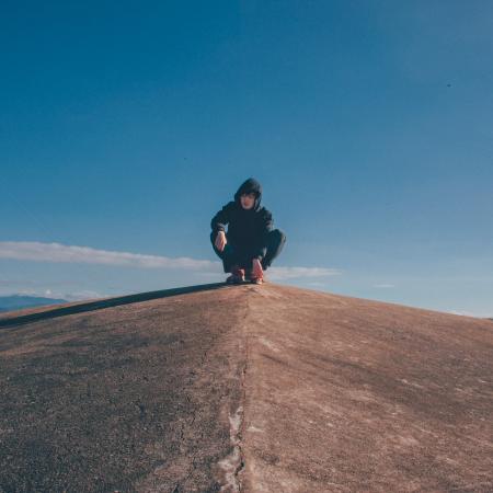Photo of Man in the Middle of Concrete Cliff