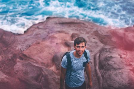 Photo Of Man Wearing Blue Shirt And Backpack Near Ocean