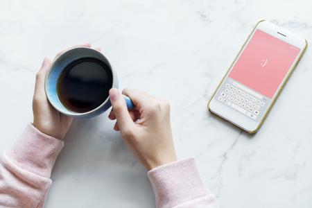 Photo of Person Holding Blue Cup Near Smartphone