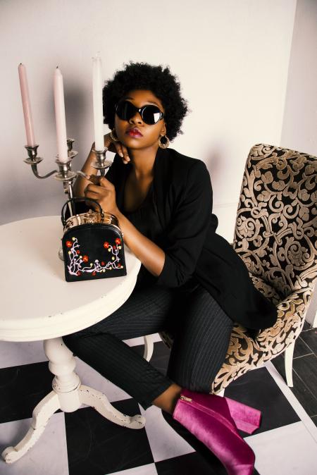 Photo of Woman Wearing Black Long-sleeved Tunic and Pinstriped Pants Sitting on Sofa Chair