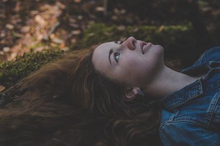 Photo of Woman Wearing Blue Denim Jacket Laying on Grass