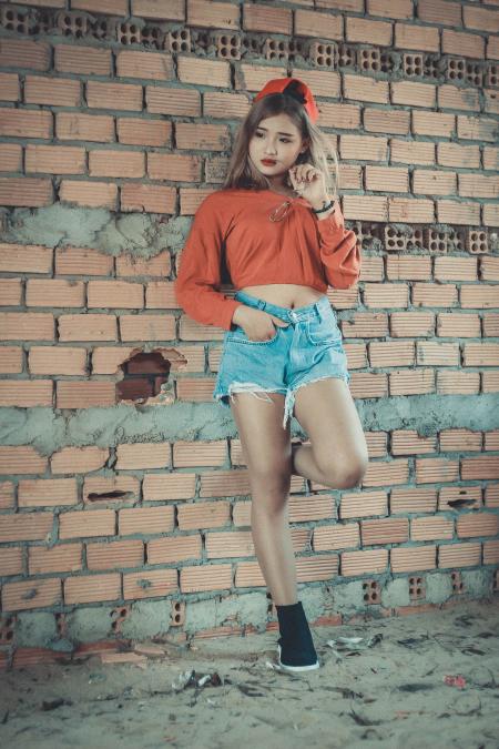 Photo of Woman Wearing Orange Crop-top Near Brown Concrete Brick Wall