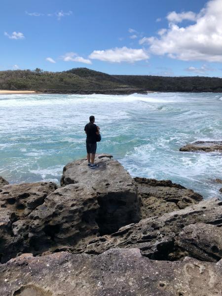 Photograph of Person on Cliff Facing Island at a Distant
