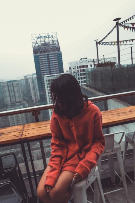 Photograph of Woman Wearing Red Pullover Hoodie Jacket Sitting on White Barstool