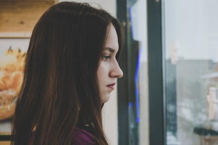 Photography of a Woman Looking Outside the Window