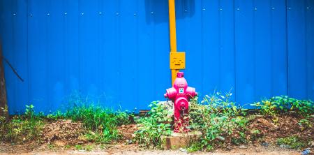 Pink Steel Water Pump Behind Blue Fence