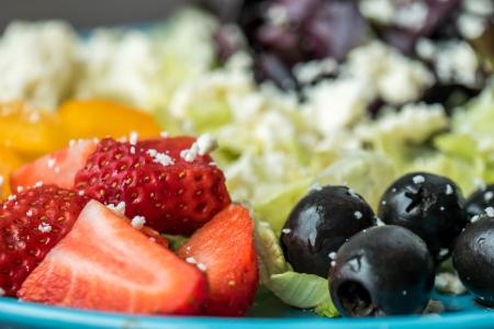 Plate of Slices of Strawberries and Green Leaf Vegetables