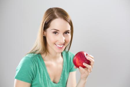 Portrait of Young Woman Eating Fruit Against White Background