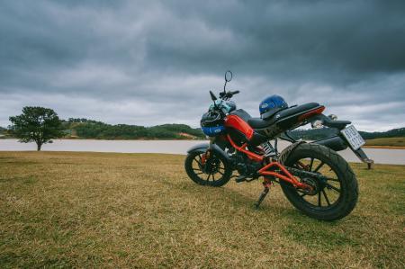 Red and Black Standard Motorcycle on Green Grass Field