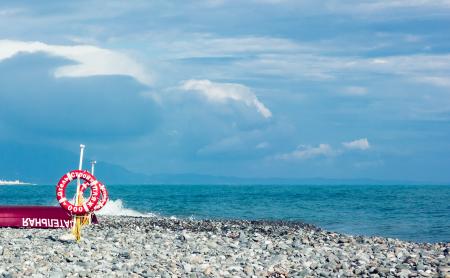 Red and White Ring Signage on Gravel Near Body of Water Under Blue and White Sky