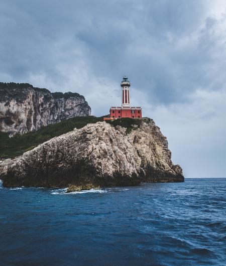 Red Lighthouse on Top of Hills Beside Sea