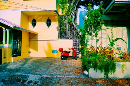 Red Motor Scooter Parked Beside the Beige Concrete Wall