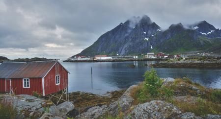 Red Wooden House Near a Mountain and River during Daytime