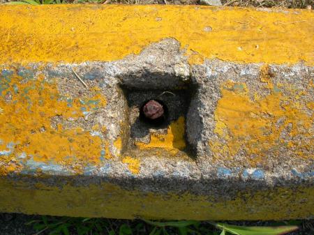 Rusted bolt in yellow concrete wall