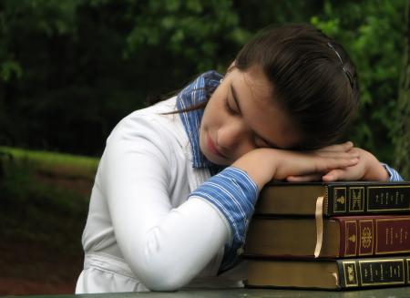Schoolgirl resting her head on books