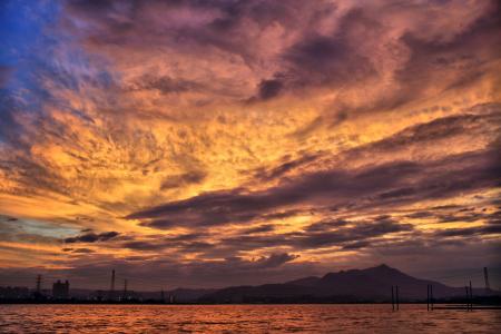 Sea and Silhouette of Mountain Under Orange Sky during Golden Hour