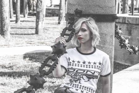 Selective Color Photography of Woman Laying Her Back at Concrete Column Holding Spike Chain