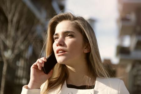 Selective Focus Photography of Woman Standing Wearing White Coat Holding Smartphone