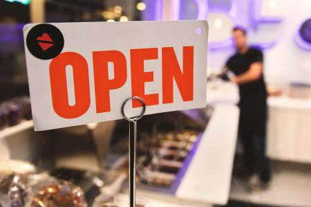 Shallow Focus Photography of Red and White Open Signage Near Man Wearing Black Shirt