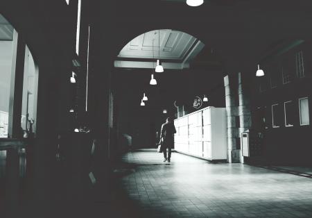 Silhouette of a Person Walking on a Grey Floor Tiles Beside White Cabinet in Dark Room