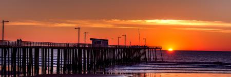 Silhouette of Boardwalk Near Body of Water Under Orange Sunset during Daytime