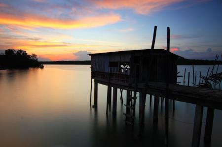 Silhouette of House on Top of Ocean Water during Sunset