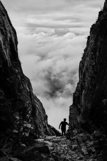 Silhouette of Man Walking Between Two Cliff