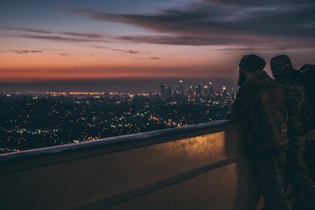 Silhouette of People Leaning on Metal Railings