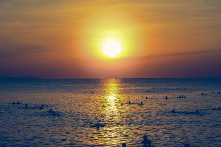 Silhouette of People Swimming in the Ocean During Sunset