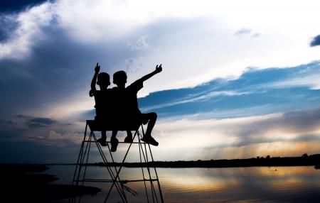 Silhouette of Two Children Looking at Body of Water