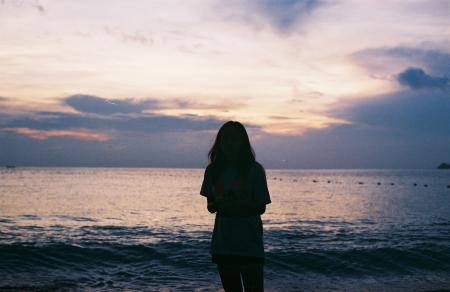 Silhouette of Woman Standing Near Large Body of Water