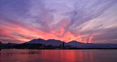 Silhouette Photo of City Buildings Near Sea With Mountain during Golden Time