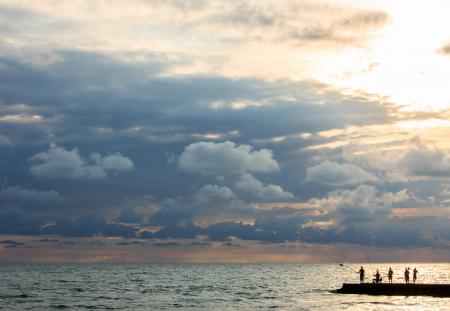 Silhouette Photo of People Standing on Dock Near Sea