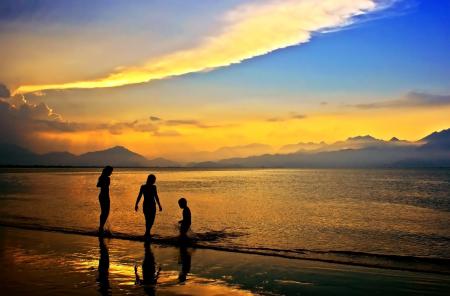 Silhouettes of 3 People in Body of Water during Dawn