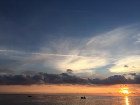 Silhouettes of People in Body of Water Under Cloudy Sky during Dusk