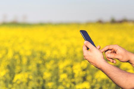 Smartphone Acer Jade S in the hands of a man on a background of yellow flowers