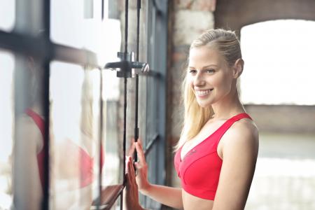 Smiling Woman In Red Brassiere Near Glass Window