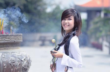 Smiling Woman in White Long Sleeved Top Holding Beige Petaled Flower Posing for Photo during Daytime