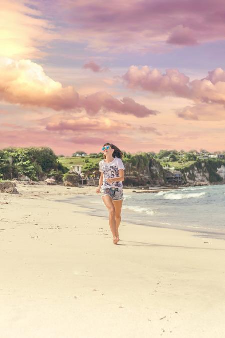 Smiling Woman Walking Barefood on Seashore Near Houses